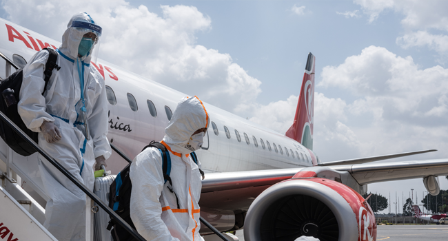 Passengers wearing full personal protective gears get off a plane at Jomo Kenyatta International Airport in Nairobi, Kenya, on January 19, 2021. Yasuyoshi CHIBA / AFP