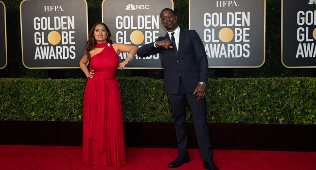 This handout photo courtesy of the HFPA shows Salma Hayek and Sterling K. Brown elbow bump as they arriving for the 78th Annual Golden Globe Awards in Beverly Hills, California on February 28, 2021. HFPA / AFP