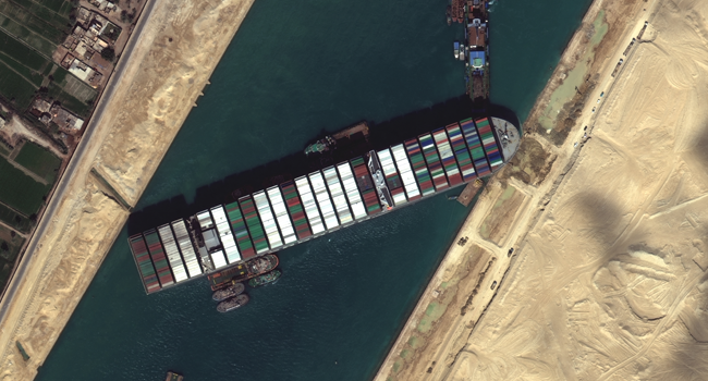 This satellite imagery released by Maxar Technologies shows tug boats and dredgers on March 27, 2021, attempting to free the Taiwan-owned MV Ever Given lodged sideways and impeding all traffic across Egypt's Suez Canal. Satellite image 2021 Maxar Technologies / AFP