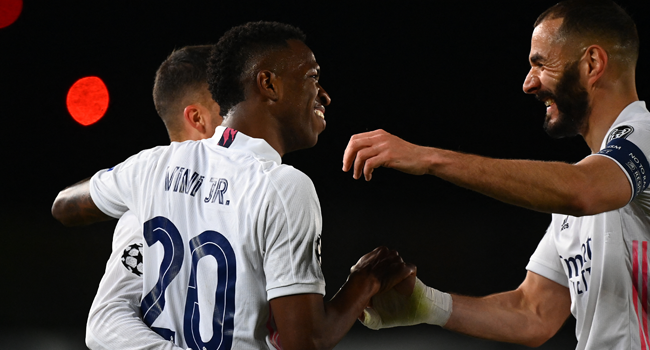 Real Madrid's Brazilian forward Vinicius Junior (C) celebrates with Real Madrid's French forward Karim Benzema (R) and Real Madrid's Spanish forward Lucas Vazquez after scoring a goal during the UEFA Champions League first leg quarter-final football match between Real Madrid and Liverpool at the Alfredo di Stefano stadium in Valdebebas in the outskirts of Madrid on April 6, 2021. GABRIEL BOUYS / AFP