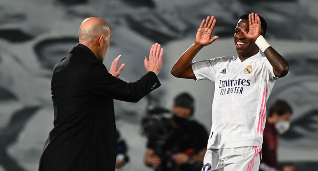 Real Madrid's Brazilian forward Vinicius Junior (R) celebrates with Real Madrid's French coach Zinedine Zidane after scoring a goal during the UEFA Champions League first leg quarter-final football match between Real Madrid and Liverpool at the Alfredo di Stefano stadium in Valdebebas in the outskirts of Madrid on April 6, 2021. GABRIEL BOUYS / AFP