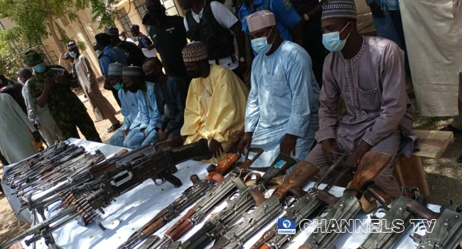 Bandit leaders stand before their surrendered guns on April 8, 2021 in Katsina State.