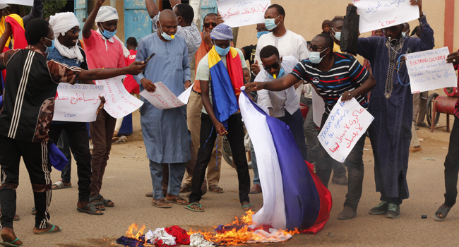 Chadian demonstrators carrying banners with anti France slogans, burn a homemade flag carrying the French colours at a protest in Ndjamena on May 8, 2021. Djimet WICHE / AFP