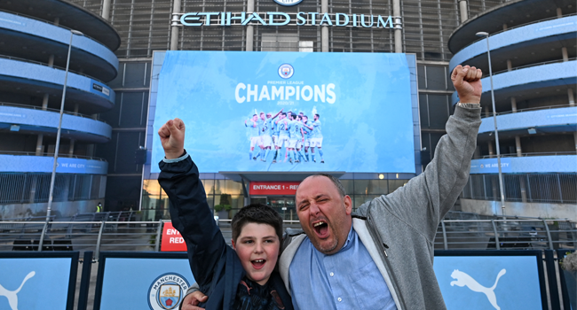 Manchester City fans, Ian Leonard and his son Jack celebrate winning the Premier League title outside the Etihad Stadium in Manchester, north west England, on May 11, 2021, after their closest challengers for the title Manchester United, lost to Leicester City this evening. Paul ELLIS / AFP