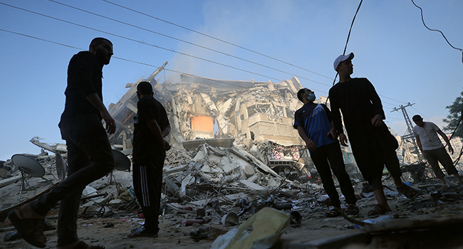 Palestinian men stand amidst debris near the al-Sharouk tower, which housed the bureau of the Al-Aqsa television channel in the Hamas-controlled Gaza Strip, after it was destroyed by an Israeli air strike, in Gaza City, on May 13, 2021. MOHAMMED ABED / AFP