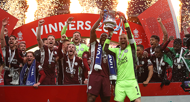 Leicester City's English-born Jamaican defender Wes Morgan (L) and Leicester City's Danish goalkeeper Kasper Schmeichel (R) hold up the winner's trophy as the Leicester players celebrate victory after the English FA Cup final football match between Chelsea and Leicester City at Wembley Stadium in north west London on May 15, 2021. Nick Potts / POOL / AFP