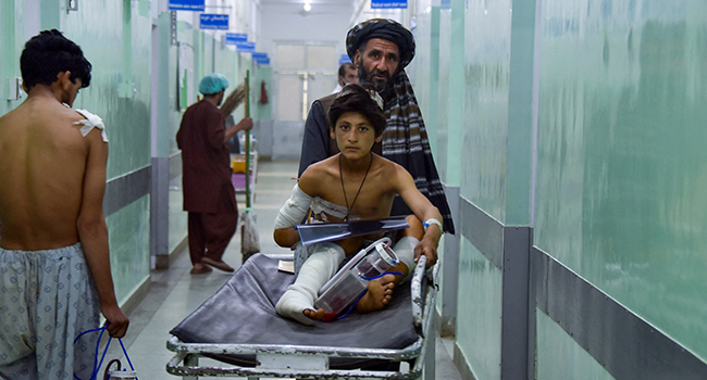 A man pushes an injured boy on a stretcher along a hospital corridor in Kandahar on May 10, 2021, as he receives medical treatment after being hurt by a roadside bomb that struck a bus overnight killing at least 11 people. Javed TANVEER / AFP