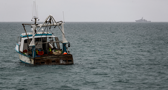 HMS Tamar (REAR), a Batch 2 river-class offshore patrol vessel of the British Navy, is watched by a fishing boat as it patrols the waters off the British island of Jersey on May 6, 2021. Sameer Al-DOUMY / AFP