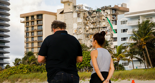 People observe the wreckage of a partially collapsed building in Surfside north of Miami Beach, Florida on June 25, 2021. Eva Marie UZCATEGUI / AFP