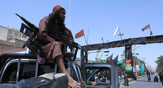 A Taliban fighter stands guard atop a vehicle near the site of an Ashura procession which is held to mark the death of Imam Hussein, the grandson of Prophet Mohammad, along a road in Herat on August 19, 2021, amid the Taliban's military takeover of Afghanistan. AREF KARIMI / AFP