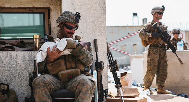 In this image courtesy of the US Central Command Public Affairs, a US Marine assigned to the 24th Marine Expeditionary Unit calms an infant during an evacuation at Hamid Karzai International Airport in Kabul on August 20, 2021. Isaiah CAMPBELL / US Central Command Public Affairs / AFP