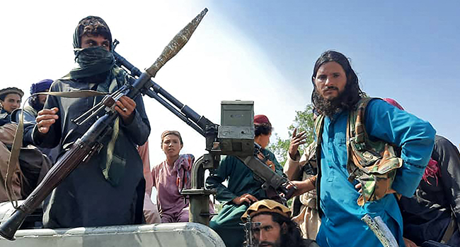 Taliban fighters sit over a vehicle on a street in Laghman province on August 15, 2021. AFP