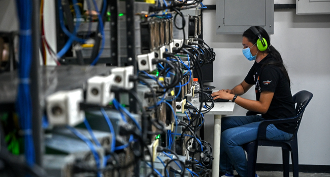 An employee inspects computers used to mine Bitcoins at the mining showroom of the Doctorminer company in Caracas on August 18, 2021. Federico PARRA / AFP