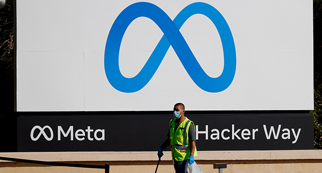 A worker picks up trash in front of a new logo and the name 'Meta' on the sign in front of Facebook headquarters on October 28, 2021 in Menlo Park, California. Justin Sullivan/Getty Images/AFP