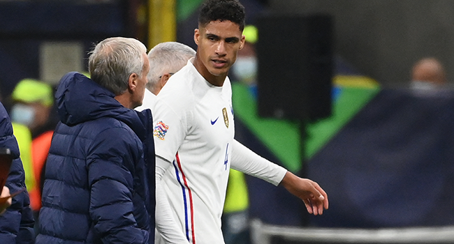 France's defender Raphael Varane (C) speaks with France's coach Didier Deschamps as he leaves the pitch after getting injured during the Nations League final football match between Spain and France at San Siro stadium in Milan, on October 10, 2021. FRANCK FIFE / AFP