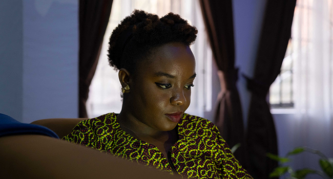 Jennifer Uchedu, a Nigerian ecofeminist, sustainability communicator and founder of SustyVibes, works on her laptop at her workspace in Ogudu, Lagos on October 31, 2021. Benson Ibeabuchi / AFP