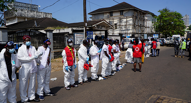 Health workers belonging to the Sierra Leone Red Cross put on protective suits ahead of a mass burial in Freetown on November 8, 2021, two days after a massive fireball sparked by a fuel tanker explosion killed almost 100 people in Sierra Leone's capital. Saidu BAH / AFP