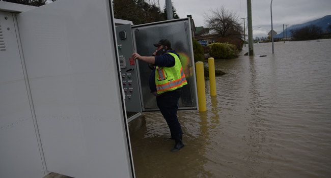 Justin McKee, an electrician with the City of Abbotsford works to restore a sewage pump control station which became flooded with water earlier this week, in the Sumas area of Abbotsford, British Columbia south of a closed Hwy 1, on November 18, 2021. PHILIP MCLACHLAN / AFP