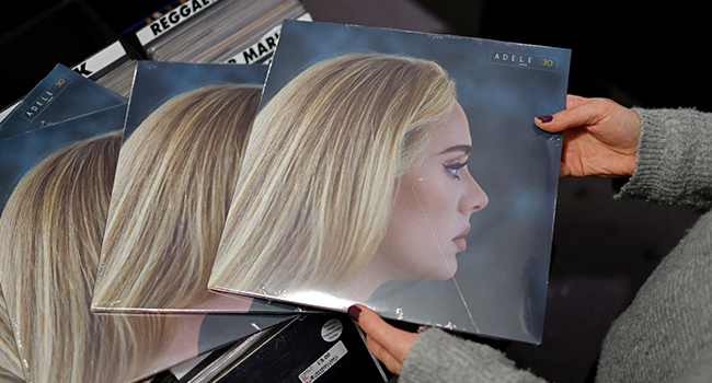 In this file photo taken on November 19, 2021, a member of staff sorts copies of the new album from British singer-songwriter Adele, "30" in Sister Ray record store in the soho area of central London. Tolga Akmen / AFP