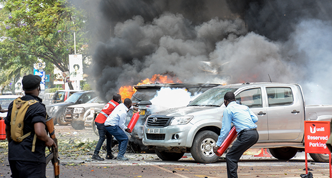 People extinguish fire on cars caused by a bomb explosion near Parliament building in Kampala, Uganda, on November 16, 2021. Ivan Kabuye / AFP