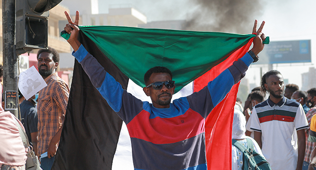 A Sudanese demonstrator lifts a national flag during a rally in Khartoum Bahri, on December 6, 2021, to protest a deal that saw the Prime Minister reinstated after his ouster in a military coup in October. AFP