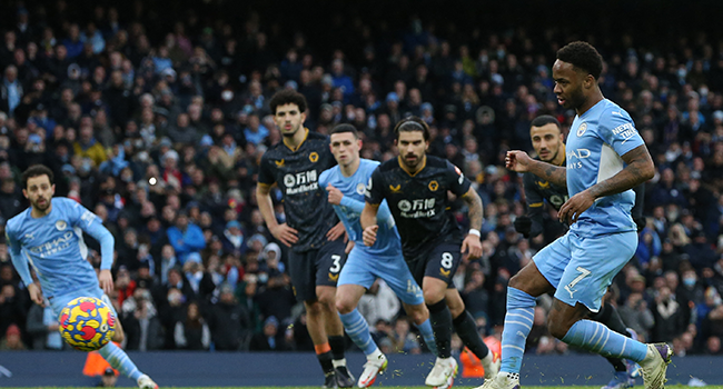 Manchester City's English midfielder Raheem Sterling (R) takes a penalty and scores his team's opening goal during the English Premier League football match between Manchester City and Wolverhampton Wanderers at the Etihad Stadium in Manchester, north west England, on December 11, 2021. NIGEL RODDIS / AFP