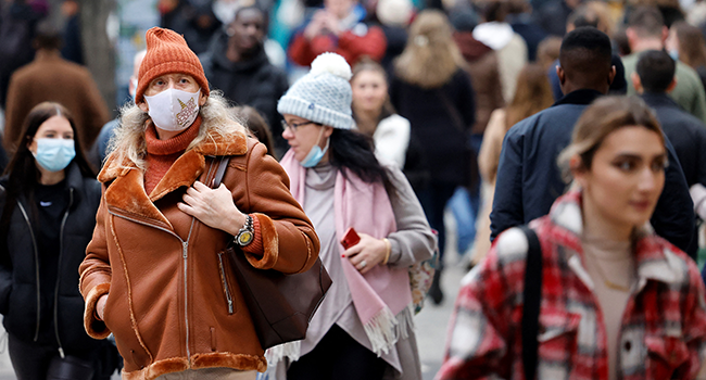 Shoppers, some wearing face coverings to combat the spread of Covid-19, walks past stores on the final Saturday before Christmas, on Oxford Street in London on December 18, 2021. Tolga Akmen / AFP