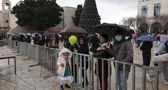 People gather outside the Church of the Nativity, revered as the site of Jesus Christ's birth, during Christmas celebrations in the biblical city of Bethlehem in the Israeli-occupied West Bank, on December 24, 2021. ABBAS MOMANI / AFP