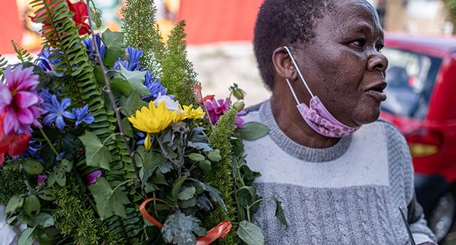 A lady holds a bouquet of flowers while mourning the passing of South African anti-apartheid icon Desmond Tutu, in front of his home in Soweto on December 26, 2021. EMMANUEL CROSET / AFP