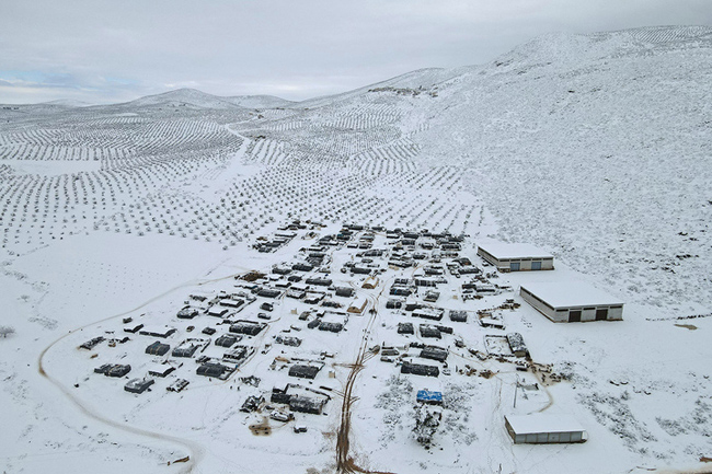 An aerial view shows a camp for internally displaced people covered in snow in the town of Raju in the rebel-controlled northern countryside of Syria's Aleppo province on January 19, 2022. (Photo by AAREF WATAD / AFP)