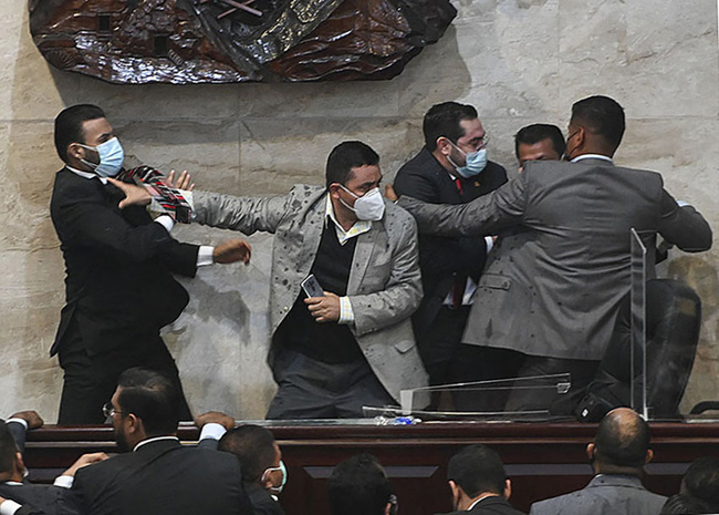Deputy for the Libertad y Refundacion (LIBRE) party Rassel Tome (L) tries to assault deputy Jorge Calix (2-R) after his election as President of the Provisional Board of Directors of the National Congress, at the Legislative headquarters in Tegucigalpa, on January 21, 2022. - The Honduran Congress elected its provisional board of directors this Friday in the midst of a brawl, with blows and shoves, because 20 members of the party that won the November presidential elections rebelled against the elected president, the leftist Xiomara Castro. (Photo by Orlando SIERRA / AFP)