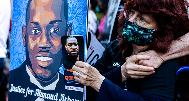 In this file photo taken on May 23, 2021 a woman holds portraits of Ahmaud Arbery and George Floyd during an event in remembrance of George Floyd in Minneapolis, Minnesota. Kerem Yucel / AFP