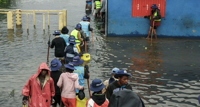 People walk through flood water after several houses were affected by rising water following heavy rains in 67 Hectares neighbourhood in Antananarivo on January 24, 2022. RIJASOLO / AFP