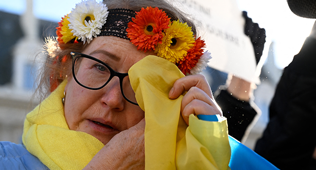 A protester wipes a tear during a rally against Russia's military operation in Ukraine at "place de la république" in Rennes, western France on February 26, 2022. DAMIEN MEYER / AFP