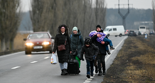 Refugees from Ukraine walk a road after crossing the Moldova-Ukrainian border's checkpoint near the town of Palanca on March 1, 2022. Nikolay DOYCHINOV / AFP