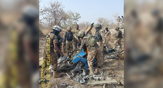 This photo, released by the Nigerian Army on March 26, 2022, shows troops standing beside what the army says are ruins of crashed Alpha Jet aircraft (NAF475).