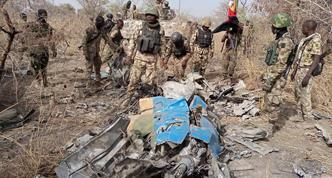 This photo, released by the Nigerian Army on March 26, 2022, shows troops standing beside what the army says are ruins of crashed Alpha Jet aircraft (NAF475).