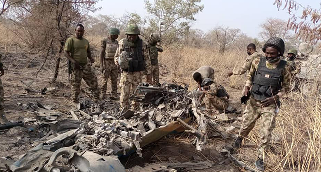 This photo, released by the Nigerian Army on March 26, 2022, shows troops standing beside what the army says are ruins of crashed Alpha Jet aircraft (NAF475).