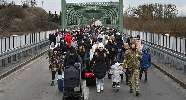 Ukrainian refugees walk a bridge at the buffer zone with the border with Poland in the border crossing of Zosin-Ustyluh, western Ukraine on March 6, 2022. Daniel LEAL / AFP