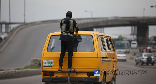 A file photo of a man behind a moving danfo bus in Lagos. Sodiq Adelakun/Channels Television