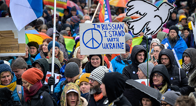 Particpants hold placards in front of the Swiss House of Parliament during a national demonstration for peace and against the war in Ukraine that gathered around 10'000 participants in Swiss capital Bern, on April 2, 2022. Fabrice COFFRINI / AFP