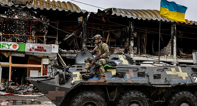 An Ukranian soldier patrols in an armoured vehicle a street in Bucha, northwest of Kyiv, on April 2, 2022, where town's mayor said 280 people had been buried in a mass grave and that the town is littered with corpses. RONALDO SCHEMIDT / AFP