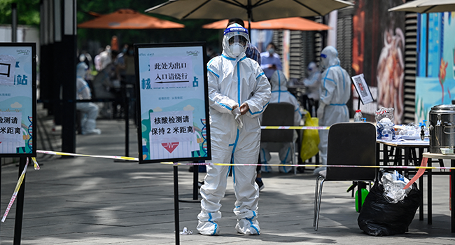 A health worker wearing personal protective equipment (PPE) stands at a Covid-19 coronavirus testing site outside a shopping mall in Beijing on May 5, 2022. Jade GAO / AFP