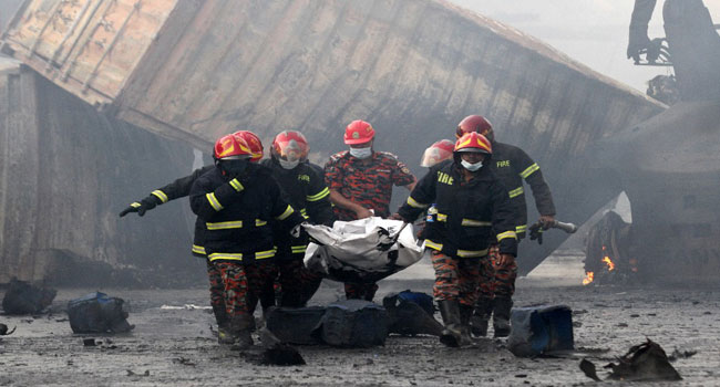 Firefighters carry the dead body of a victim from the site after a fire broke out at a container storage facility in Sitakunda, about 40 km (25 miles) from the key port of Chittagong on June 5, 2022.