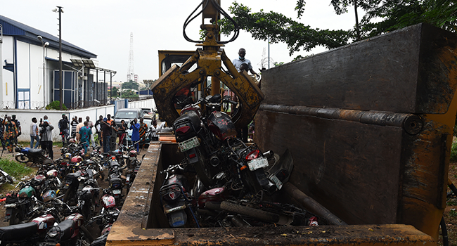 A crane lifts taxi motorcycles, popularly called Okada, to be crusched that were seized by the Lagos Environmental Task Force following a ban on bike transport in Lagos on June 3, 2022. PIUS UTOMI EKPEI / AFP