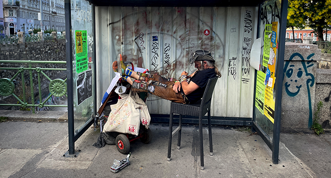 A homeless man takes a nap at a bus stop in Vienna, Austria on June 23, 2022. JOE KLAMAR / AFP