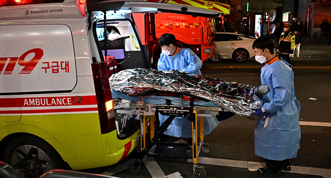 The body of a victim of a Halloween crush, which left at least 120 people dead, is transported on a stretcher into an ambulance in the district of Itaewon in Seoul on October 30, 2022. (Photo by Jung Yeon-je / AFP)