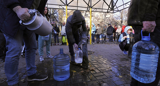 Local residents wait in line to collect water from a public water pump in a park of Kyiv on October 31, 2022. (Photo by SERGEI CHUZAVKOV / AFP)