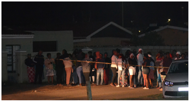 Bystanders wait behind a police tape marking the scene of a mass shooting in Gqeberha, South Africa, on January 29, 2023. (Photo by Luvuyo Mehlwana / AFP)