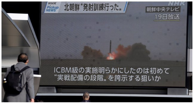 Pedestrians walk past a screen in Tokyo on February 20, 2023, displaying North Korea's missile launch footage broadcasted by Korean Central Television on February 19. (Photo by Kazuhiro NOGI / AFP)